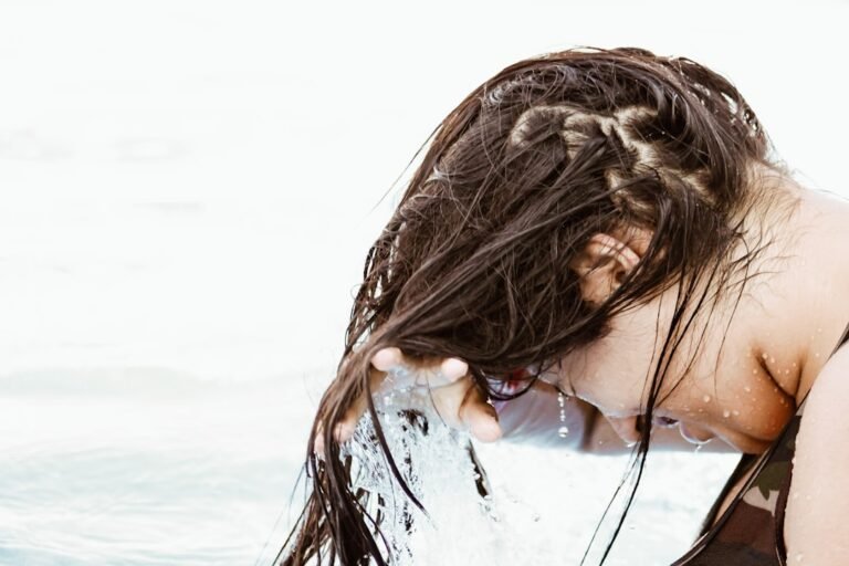 A person washing their hair in a bathroom, showcasing proper technique and care with water and shampoo.