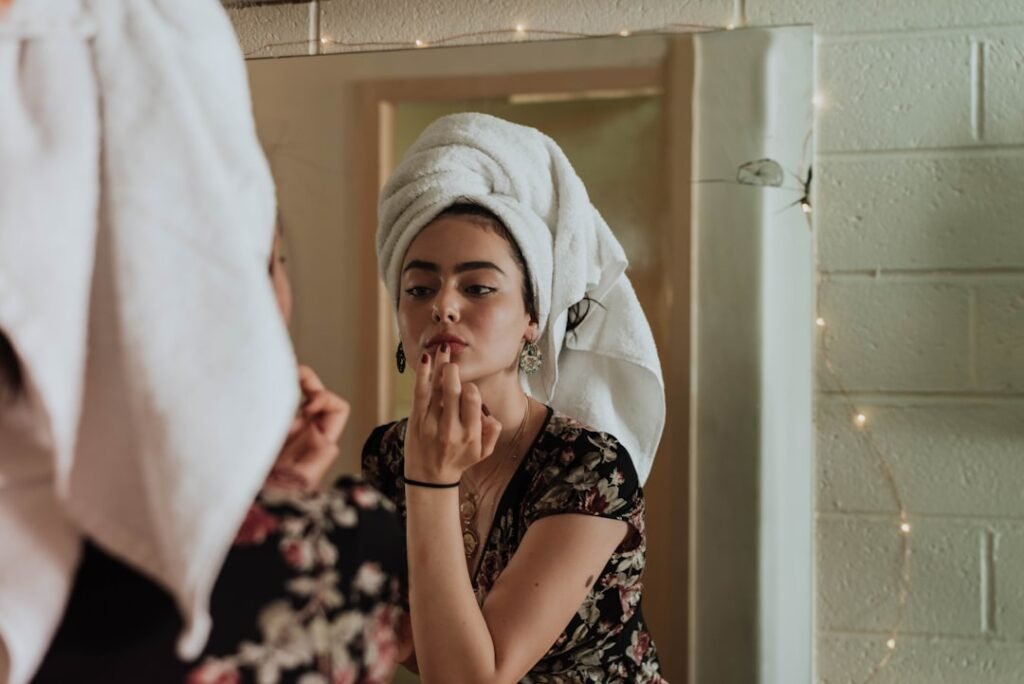 A close-up of a person applying skincare products with a thoughtful expression, surrounded by various skincare items like creams and serums.