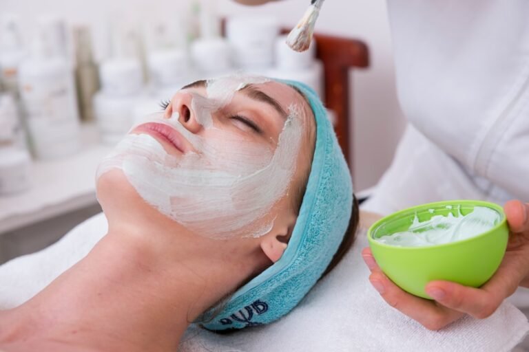 A close-up of a woman's hand applying moisturizer to her face, showcasing healthy and glowing skin.