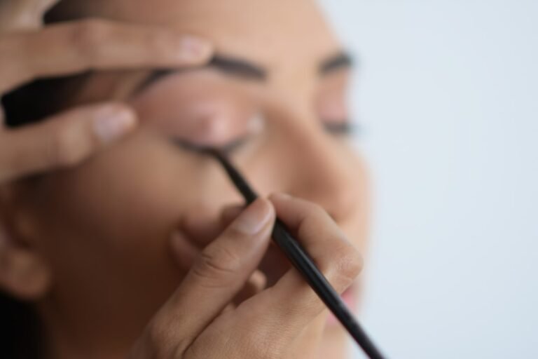 A close-up of a makeup artist applying foundation and setting powder on a model's face, showcasing techniques for long-lasting makeup.