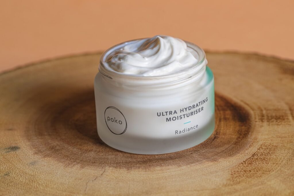 A close-up of a light moisturizer being applied to a hand, with a background of fresh green leaves to symbolize hydration and skin health.